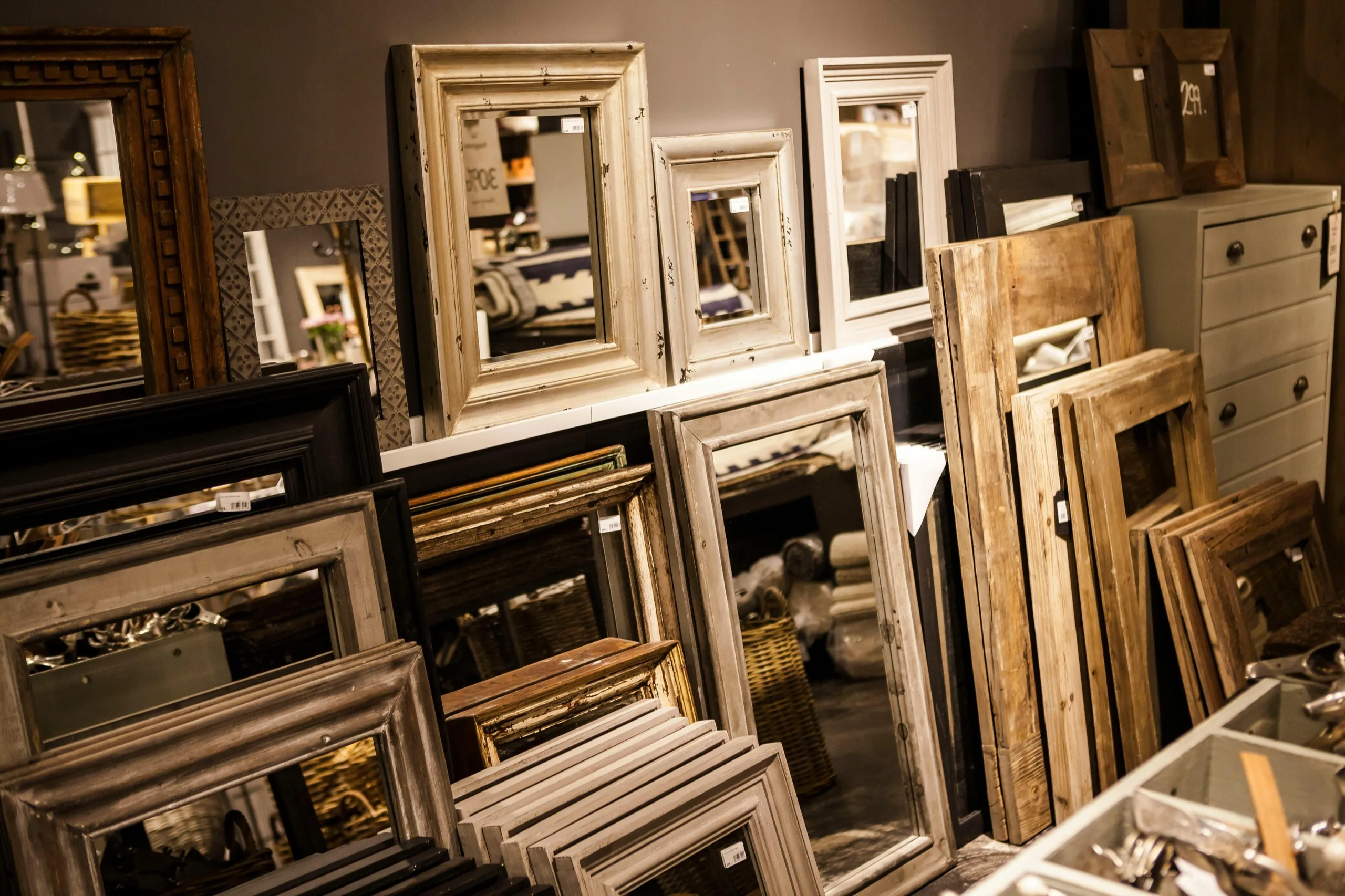 Wall of finished custom picture frames in a range of moulding profiles and finishes